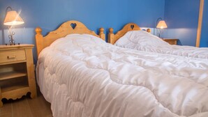 A double bed with a wooden headboard, two bedside tables with lamps, and a wooden nightstand with a drawer.