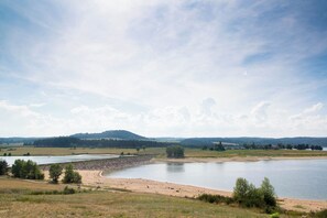 A wide river with a sandy bank and a forested hill in the background.
