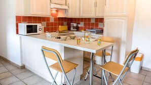 Une cuisine compacte équipée d’un four à micro-ondes, d’un grille-pain et d’une petite table à manger avec des chaises.