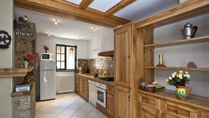Una cocina con armarios de madera, un refrigerador, una estufa y una ventana.