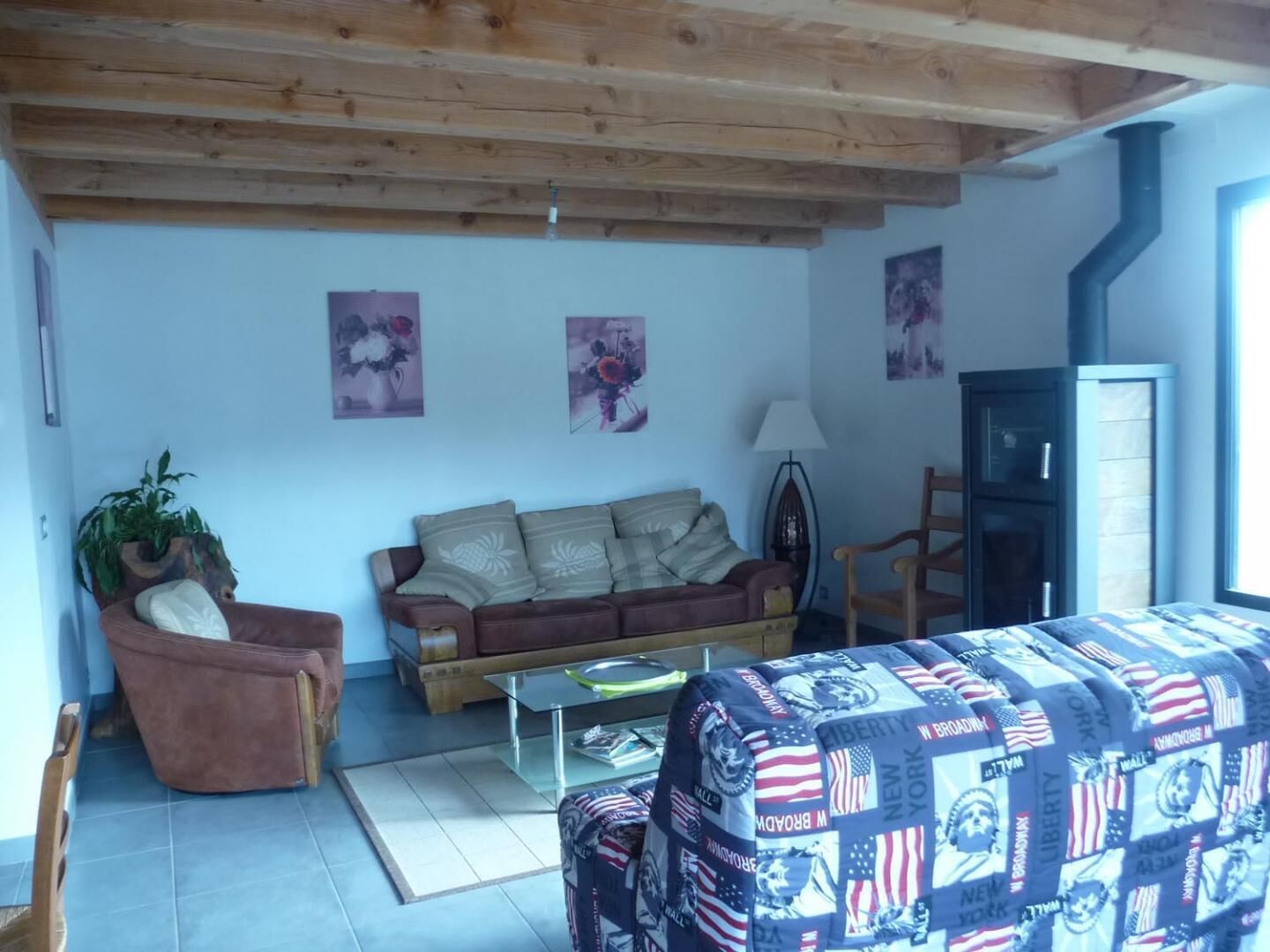 Ein Wohnzimmer mit Holzbalkendecke, einem braunen Sofa, einem Glastisch und einer Decke mit amerikanischen Flaggen.