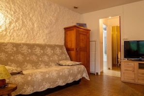 Una sala acogedora con un sofá estampado con motivos florales, un aparador de madera y un televisor.