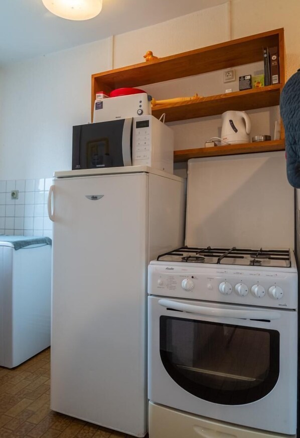 A compact kitchen with a refrigerator, microwave, stove, and oven.