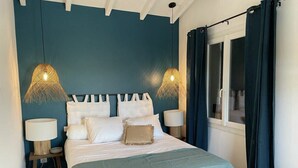 Une chambre à coucher avec un lit, des lampes de chevet, une fenêtre avec des rideaux et un mur peint dans une couleur turquoise.