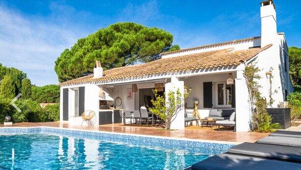 Une villa avec piscine, un espace salon extérieur et un jardin.