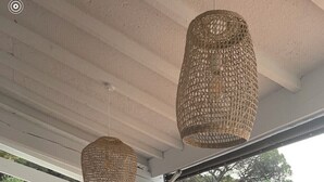 Une terrasse extérieure avec une piscine, des guirlandes lumineuses en osier, une table à manger et des sièges.