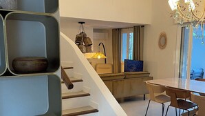Un intérieur moderne avec un escalier menant à une salle à manger, un lustre et un téléviseur.
