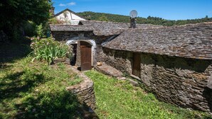 Un bâtiment en pierre, doté d’une antenne parabolique, d’une porte en bois et d’un petit jardin fleuri.