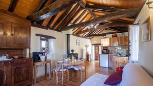 Un intérieur rustique avec des poutres en bois, un coin repas, une cuisine et un lit.