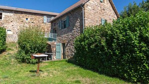 A stone building with a small balcony, surrounded by greenery and a grassy area. - Le Four, Ferme de la Beyssiere (PIED DE BORNE)
