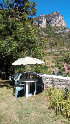 Un espace extérieur aménagé avec une table et des chaises, un parasol et une vue sur une montagne rocheuse.