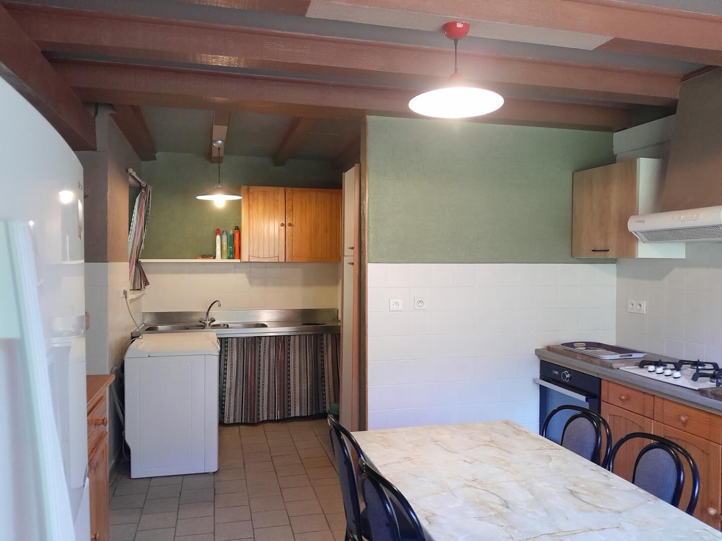 A compact kitchen with a refrigerator, stove, sink, and wooden cabinets.