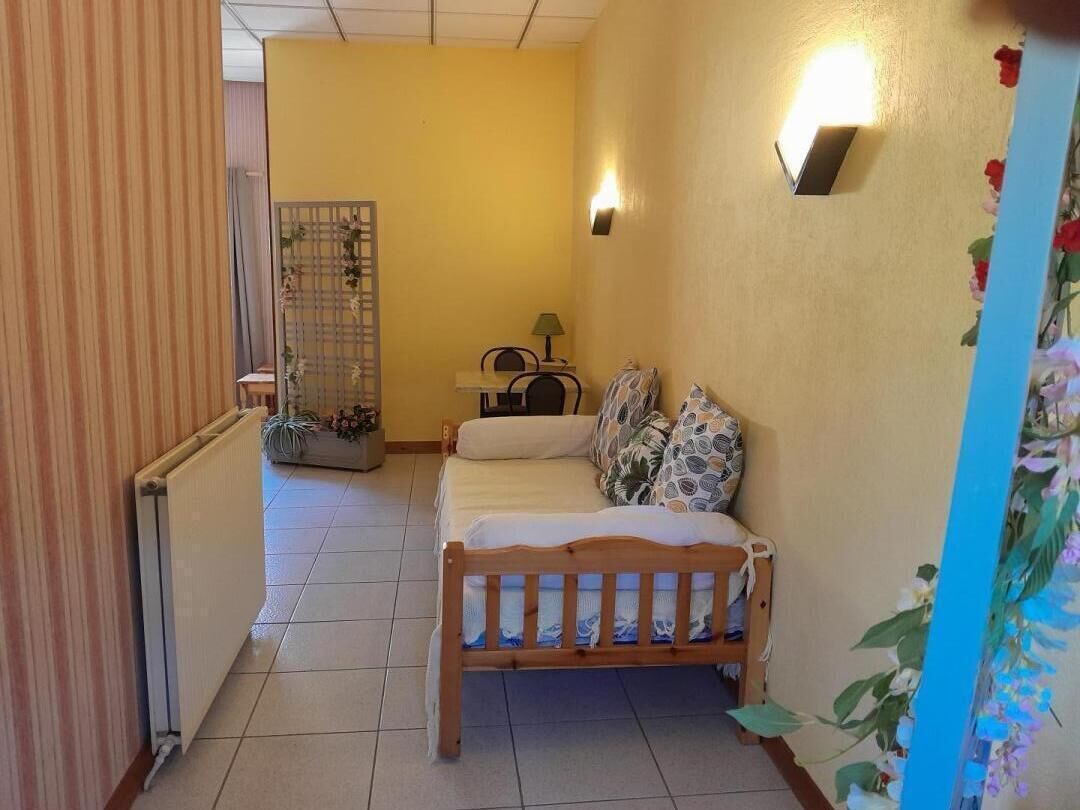 Ein kleines Zimmer mit einem Bett, einem Sessel, einem Tisch und einer Heizung.