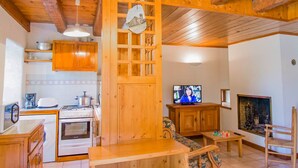 A cozy kitchen with wooden cabinets, a dining area with a wooden table, and a television in the living room.