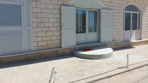 A building with a brick facade, white shutters, and a small porch area. - Apartments K & N -One Bedroom Apartment A2 (Prižba)