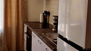 A kitchen with white cabinets, a stainless steel refrigerator, and a coffee maker. - Apartments K & N -One Bedroom Apartment A2 (Prižba)