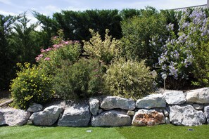 A landscaped garden with various shrubs and a stone wall.