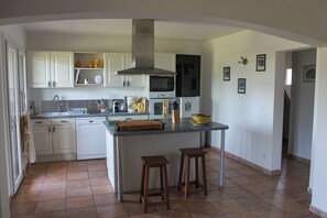 Een keuken met witte kastjes, een centraal eiland, een magnetron en een fornuis.