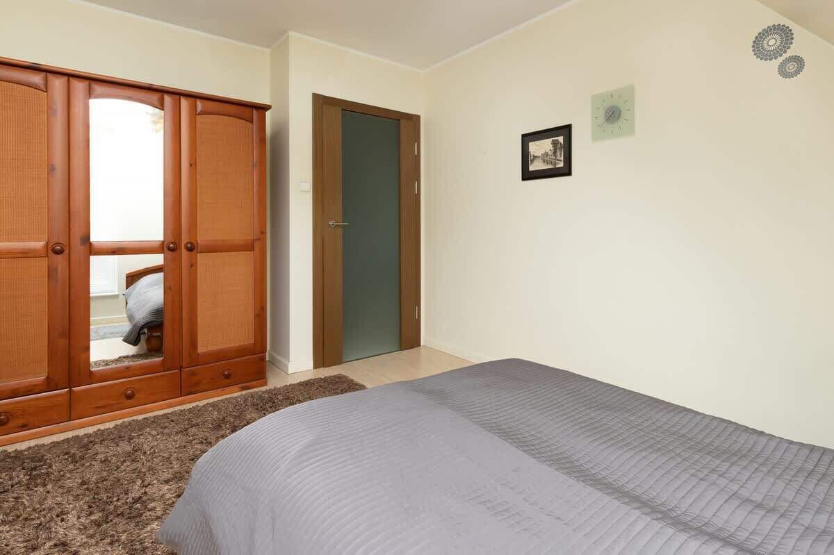 Ein Schlafzimmer mit Bett, Kleiderschrank, Tür und Wanduhr.