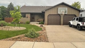 Un garage attenant à une maison, équipé d’un panier de basketball, avec une allée et un VUS blanc garé devant.