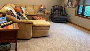 Un salon chaleureux avec un canapé marron, un fauteuil en cuir et une table basse décorée de bougies.