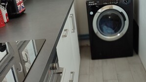 A compact kitchen with a modern design, featuring a built-in oven, a sink, and a washing machine. - Grand Logement Rénové, 84 m2, 5 Personnes, à 100 m de la Gare et du Tramway (Le Havre)