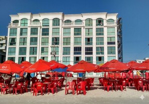 A hotel with multiple floors, large windows, and red umbrellas.