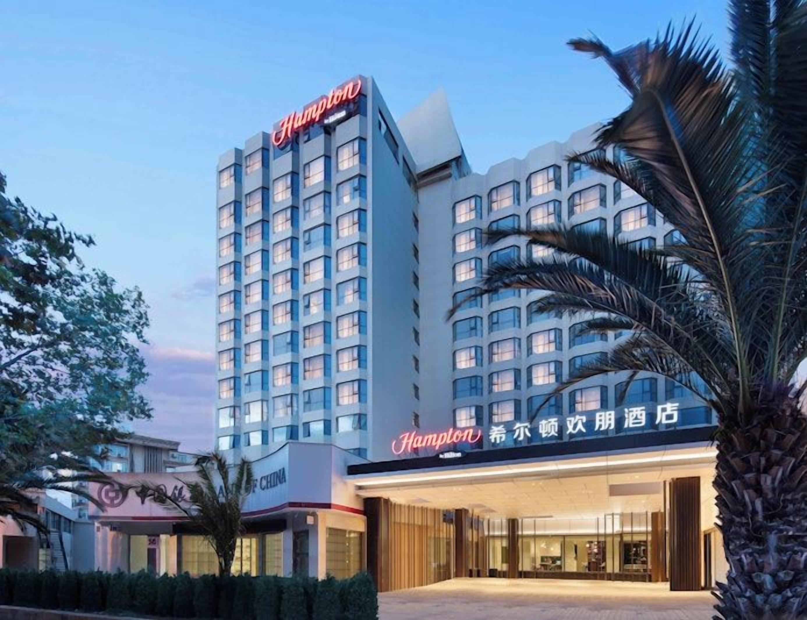 Een hotel met een opvallend Hampton bord, een Chinees restaurant en een goed verlichte ingang.