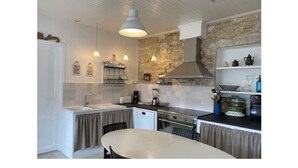 Cozinha compacta com parede de destaque em pedra, área de refeições com mesa redonda e iluminação pendente.