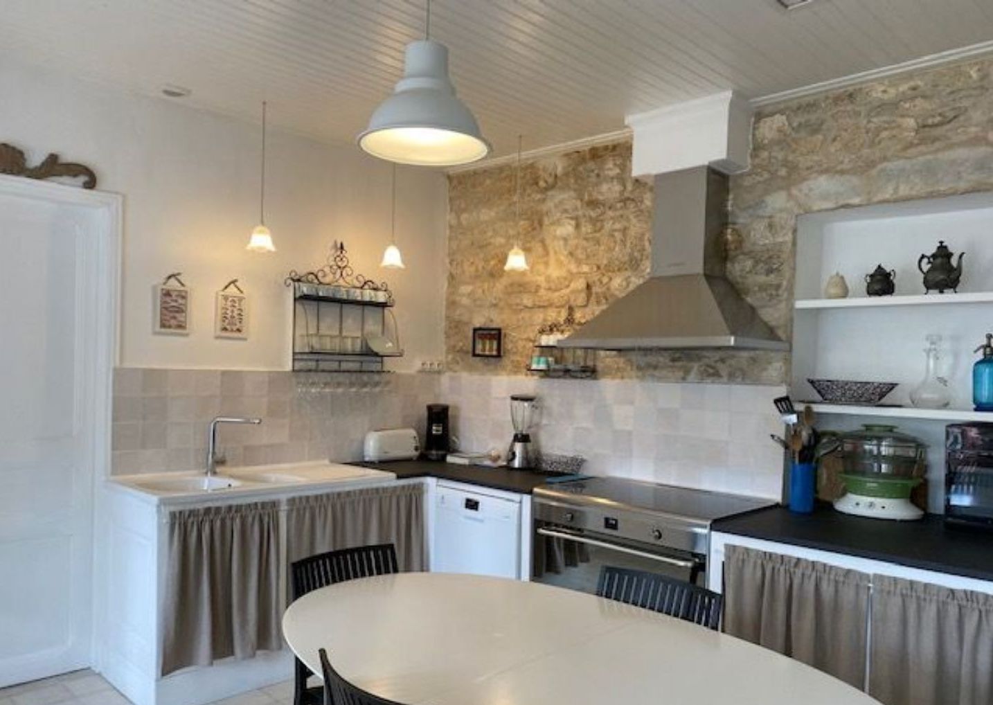 A compact kitchen with a stone accent wall, a dining area with a round table, and pendant lighting.