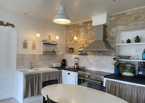 A compact kitchen with a stone accent wall, a dining area with a round table, and pendant lighting.