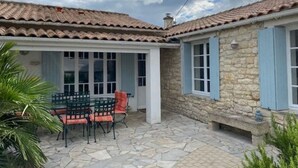 Um edifício de pedra com telhado em cerâmica e um pátio com mesa e cadeiras.