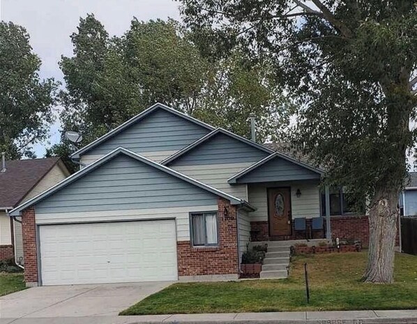 Stunning two-story home with a garage door, brickwork, and a charming front porch.