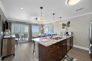 A kitchen with a granite countertop, wooden cabinets, and pendant lighting. - New heated pool & Hot TUB! Extraordinary! (Galveston)