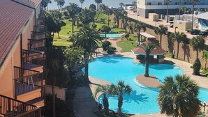 Ett hotell med en swimmingpool, palmer och utsikt över havet.