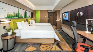 Habitación de hotel con dos camas, un escritorio con silla, televisor y pantalla en la pared.