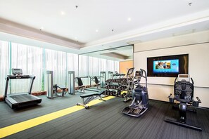 Un gimnasio con cintas de correr, elípticas y pesas libres.