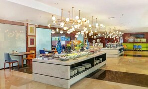A modern hotel lobby with a buffet area, a seating area with chairs, and a television mounted on the wall. - Hampton By Hilton Zhuhai Gongbei Port (Zhuhai)
