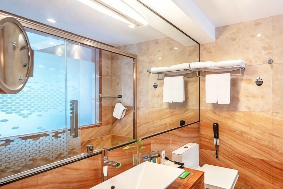 Un baño moderno con cabina de ducha de vidrio, un espejo grande y un lavabo blanco.