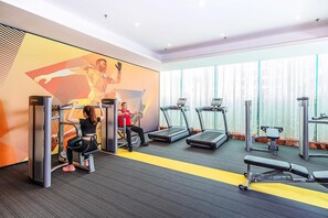A gym with treadmills, a bench press, and a woman exercising. - Hampton By Hilton Zhuhai Gongbei Port (Zhuhai)