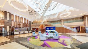 A spacious lobby with a central seating area, a reception desk, and a staircase leading to upper levels.