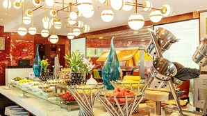 A buffet with various food items, a decorative glass vase, and a unique metal sculpture.