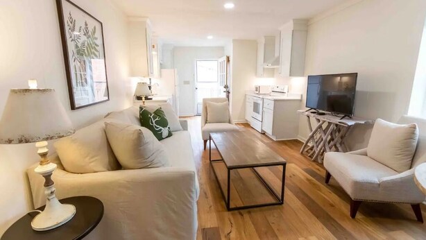 A modern living room with a sofa, a coffee table, and a TV. There is a kitchen area with a microwave and a dining table. - Historical Hotel, Main Street Blowing Rock (Blowing Rock)