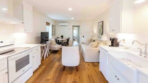 A modern kitchen with white cabinets, a dining area with a table and chairs, and a living area with a sofa and a TV. - Historical Hotel, Main Street Blowing Rock (Blowing Rock)