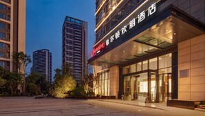 Een modern hotel met een opvallend bord, grote ramen en een goed verlichte ingang.
