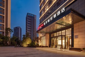 A modern hotel with a prominent sign, large windows, and a well-lit entrance. - Hampton BY Hilton Chengdu Wciec (CHENGDU)
