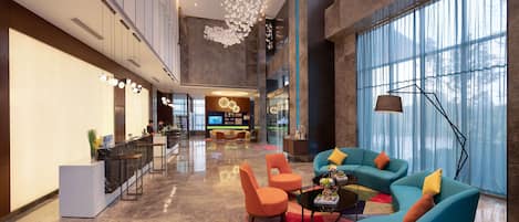 A spacious lobby with a reception desk, seating area, and large windows.