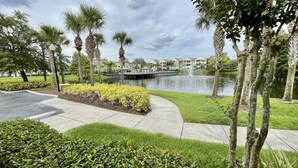 A landscaped area with a pond, palm trees, and a bridge. - Lake view gorgeous condo 3bd - 10 min from Disney (Kissimmee)