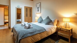 A bedroom with a bed, two bedside tables with lamps, a wooden wardrobe, and a mirror. - Modern Comfortable Apartment with Balcony and Garage. Great Location for Skiing. (Samoëns)