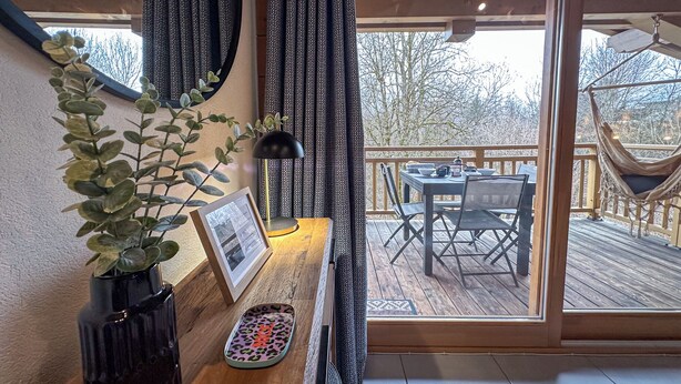 A wooden deck with a dining table and chairs, a hammock, and a potted plant. - Modern Comfortable Apartment with Balcony and Garage. Great Location for Skiing. (Samoëns)